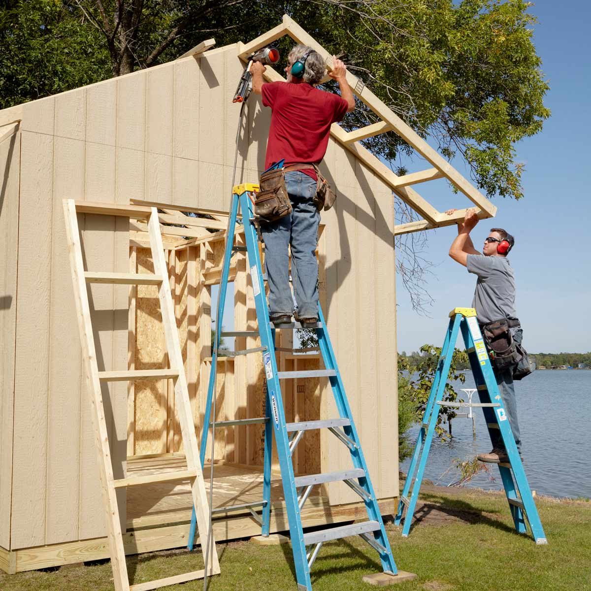 Men on ladders add an overhang to a shed