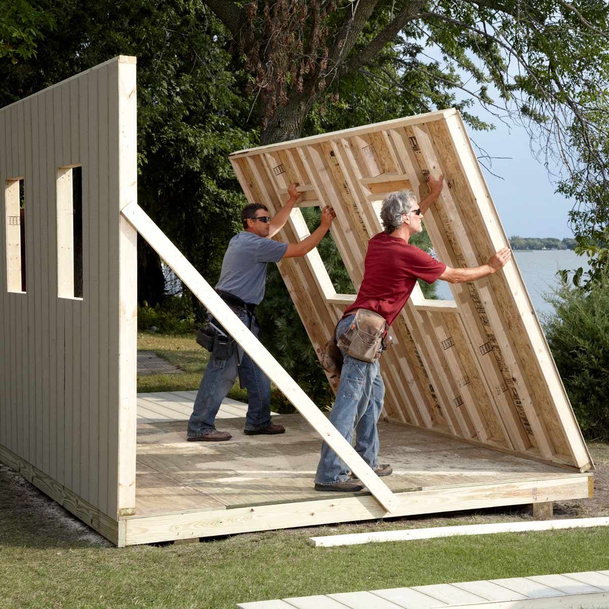 two men raise a shed wall overlook a lake