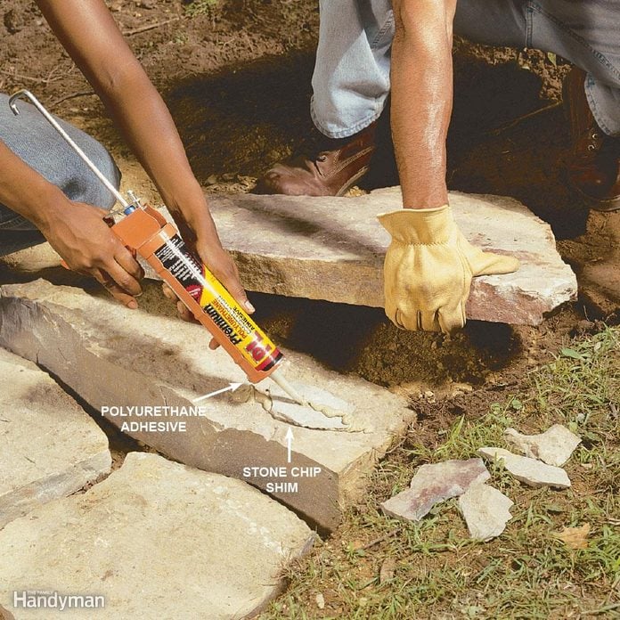 woman applies polyurethane adhesive to stone landscaping
