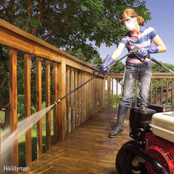 woman power washes a deck