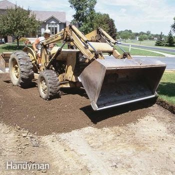 excavator drives over dirt to build an asphalt driveway