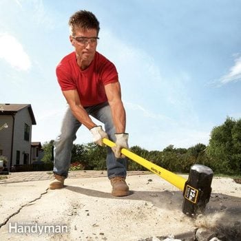 Man uses a sledghammer to break up concrete