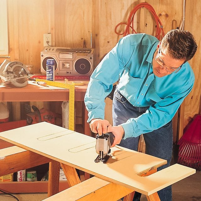 A Man Cutting Wooden Board with Jigsaw