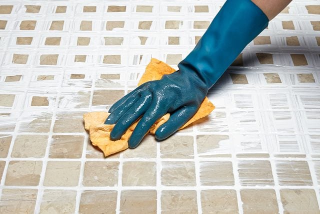 How To Whiten Grimy Grout, Cleaning Extra Grout on Tiles with Cloth with Hand wearing Rubber Gloves