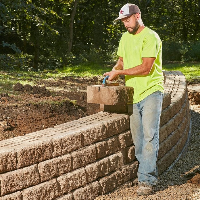 Man placing blocks onto a retaining wall | Construction Pro Tips