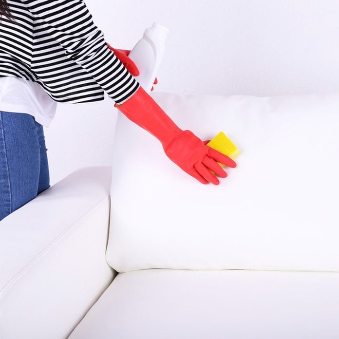 shutterstock_195200609 cleaning white couch furniture with natural cleaners rubber gloves