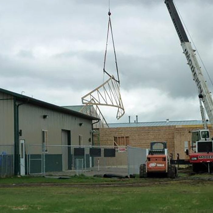Hoisting Trusses over other buildings to put them in place | Construction Pro Tips