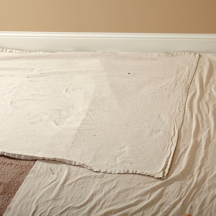 Laying down narrow drop cloths next the walls | Construction Pro Tips
