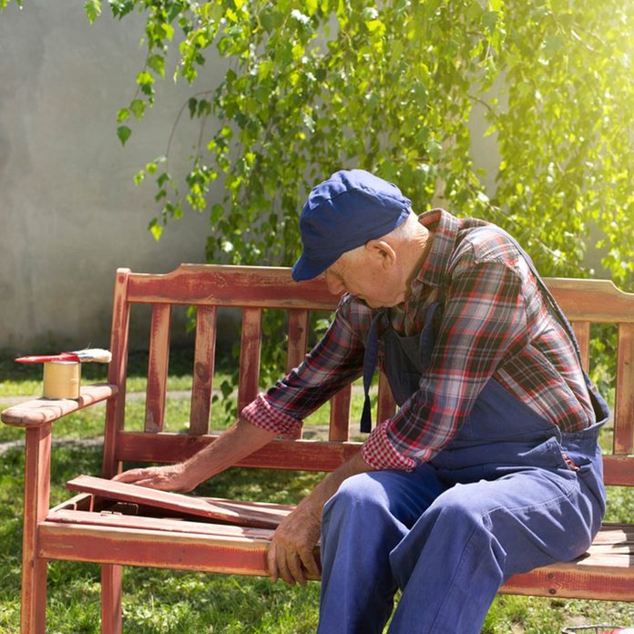 Grandpa Man fixing a bench painting outdoor furniture