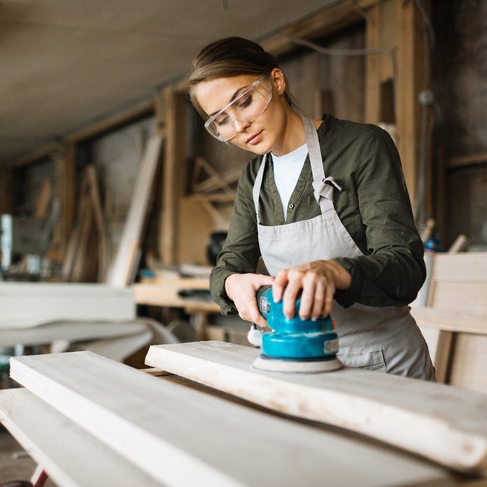 woman sanding with safety glasses