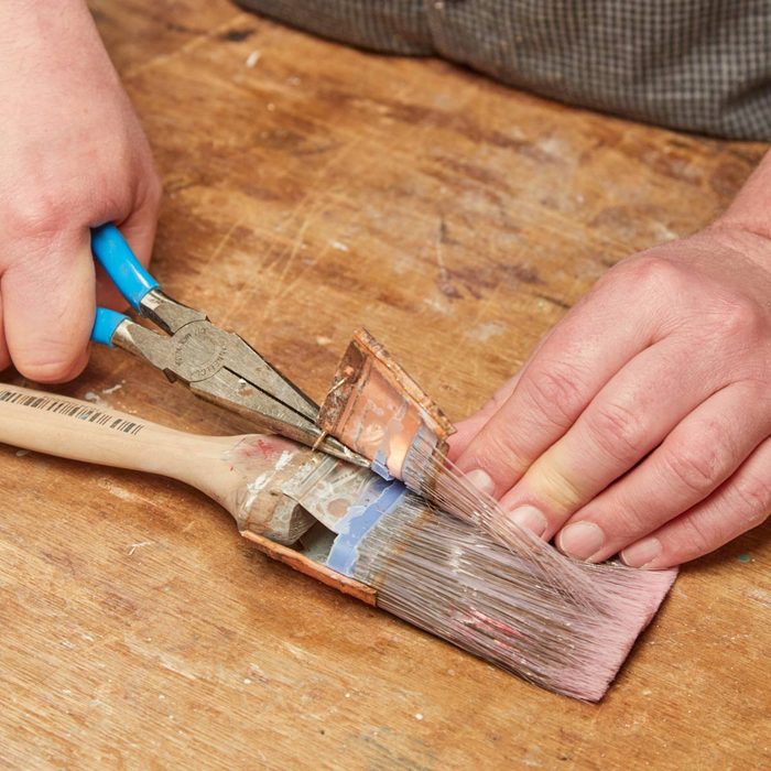 using pliers to take apart old paint brush