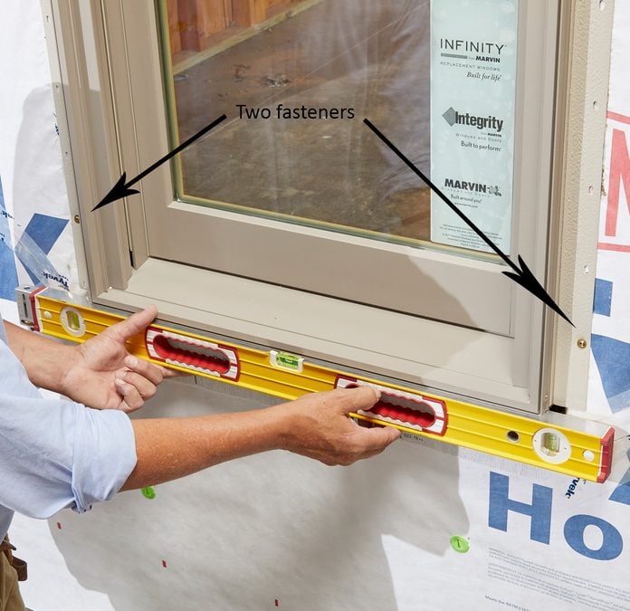 Man leveling and fastening the bottom of a window | Construction Pro Tips