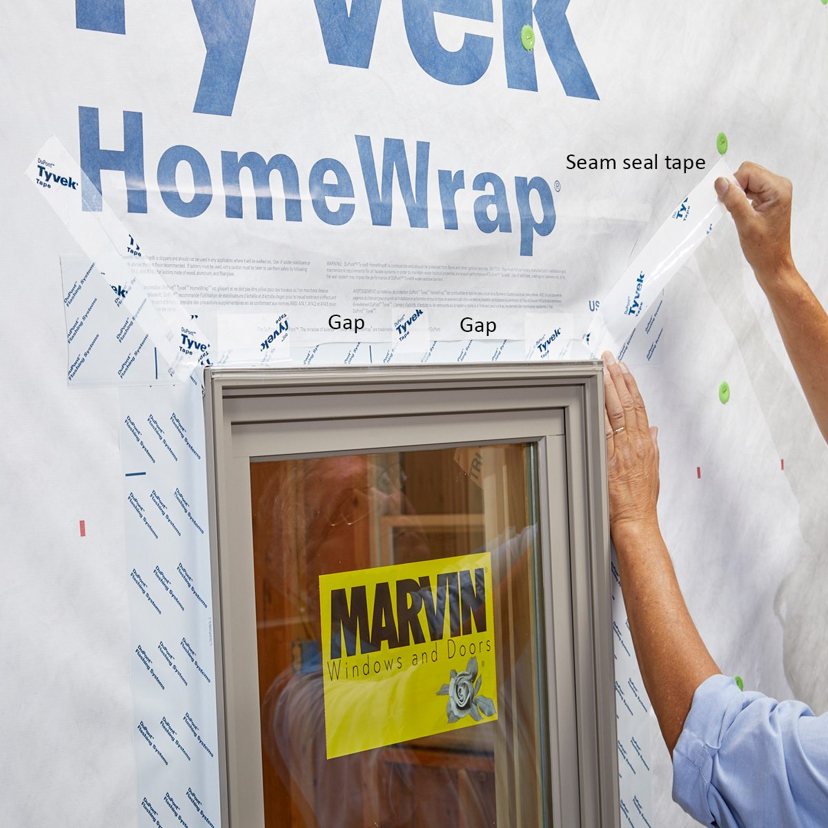 Taping the top flaps of Tyvek down after window installation | Construction Pro Tips