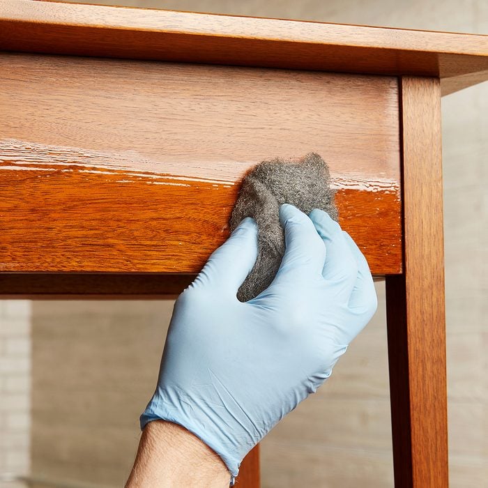Wiping final coat of poly onto wood project with steel wool | Construction Pro Tips