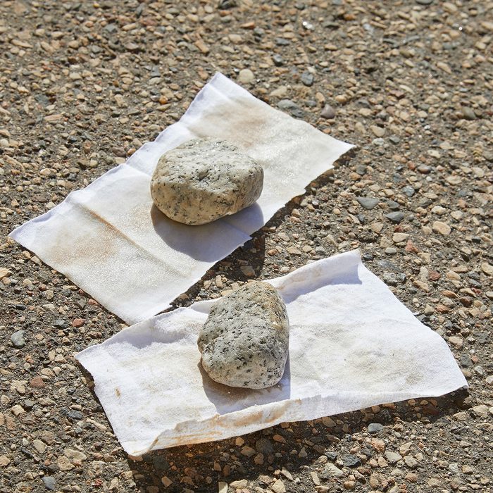Rocks weighing down two oily rags on ground | Construction Pro Tips