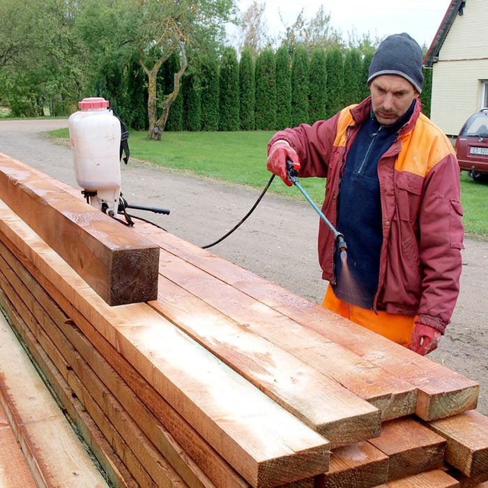 Man spraying treatment onto lumber | Construction Pro Tips