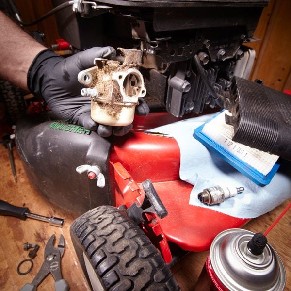 lawn mower carburetor being removed for inspection
