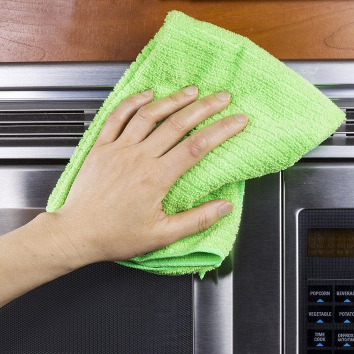 Hand with microfiber rag cleaning vents of microwave oven; Shutterstock ID 121364071; Job (TFH, TOH, RD, BNB, CWM, CM): Taste of Home