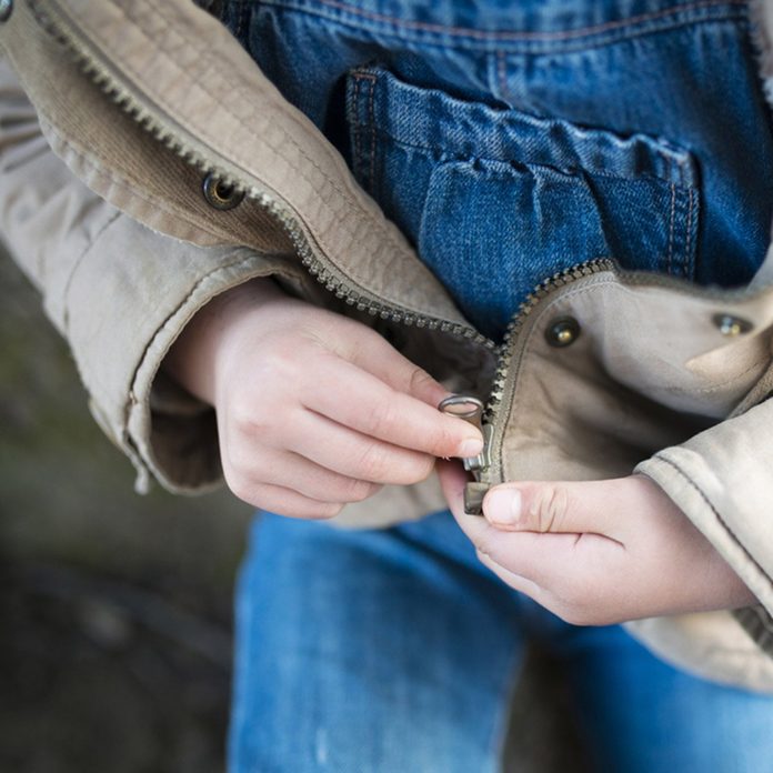 Child trying to close a zipper; Shutterstock ID 566069029