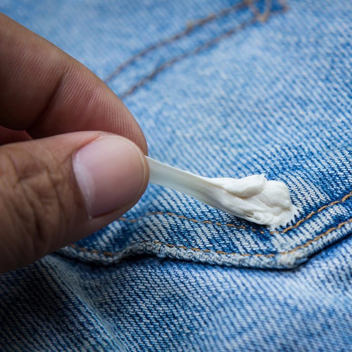 Gum sticking on jean with holding hand of food stain on clothes of daily life ; Shutterstock ID 592614866