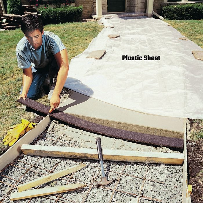 Man laying plastic sheets over concrete | Construction Pro Tips