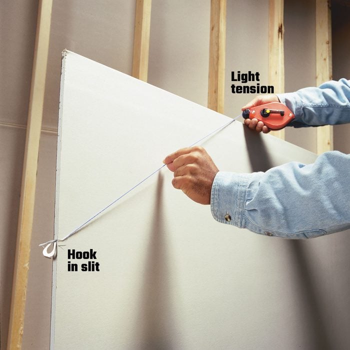 Making a line on a piece of drywall with a chalk line | Construction Pro Tips
