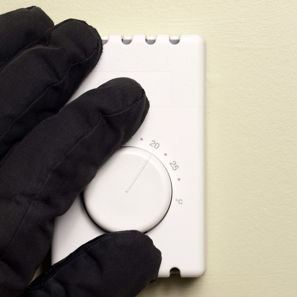 hand with glove changing thermostat