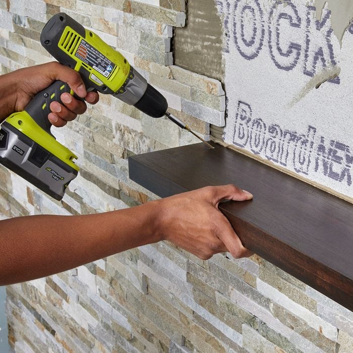 Attaching a shelf during stone wall installation 