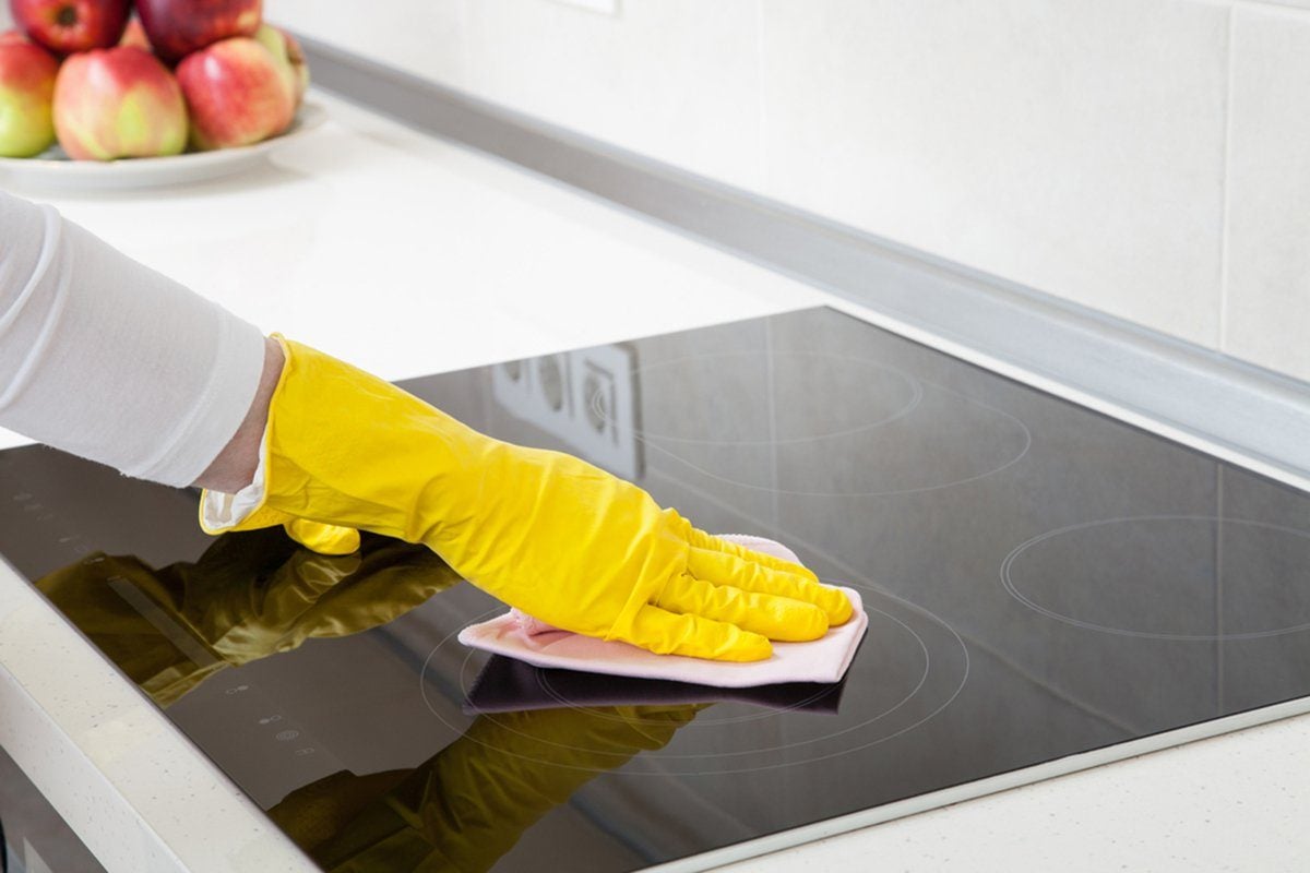 woman showing how to clean a glass stovetop