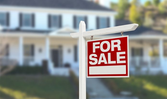 Home For Sale Real Estate Sign in Front of Beautiful New House.