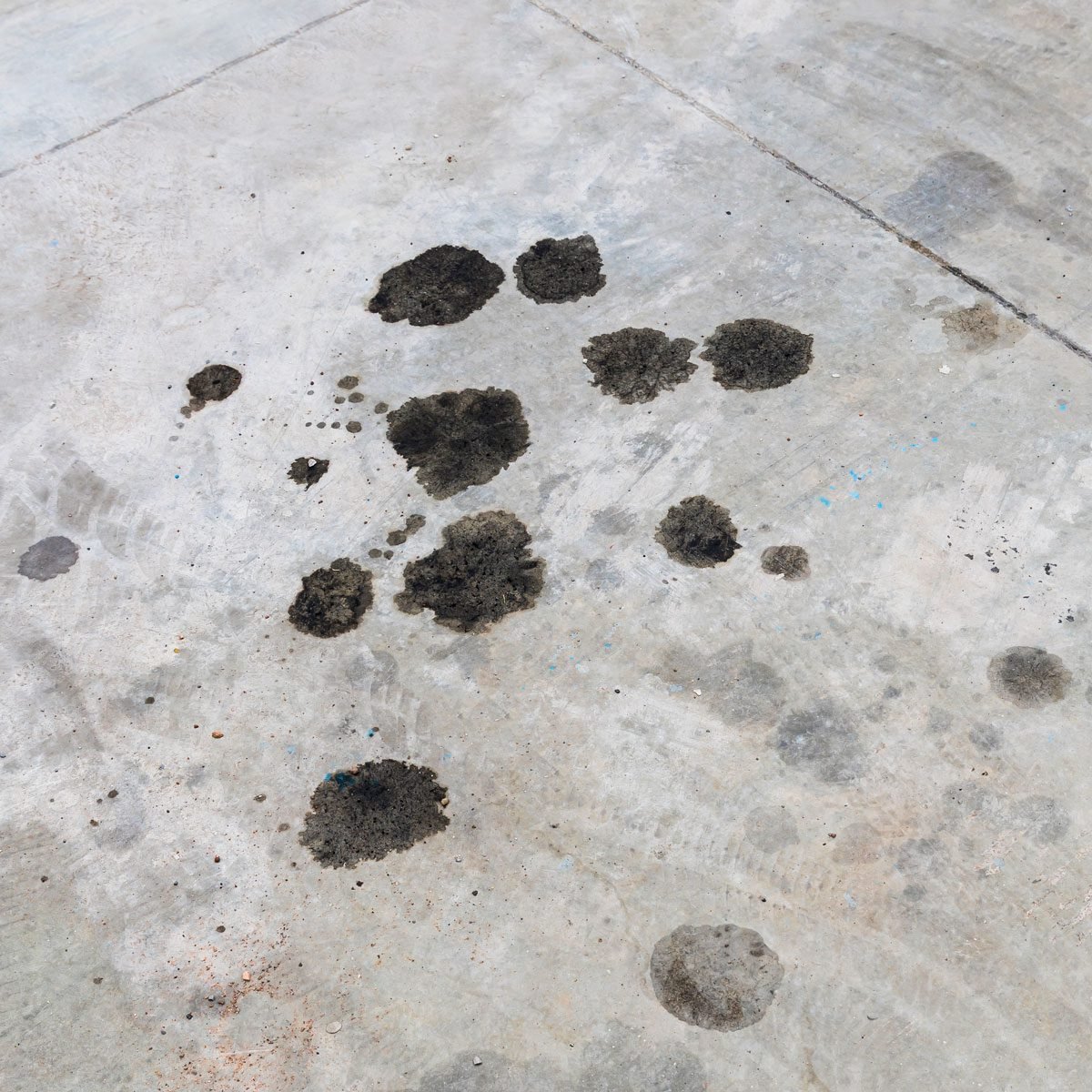 Engine Oil Leakage On Concrete Floor. Black Engine Oil On Concrete Floor. Engine Oil Leak From The Engine.  Surface Concrete With The Motor Oils Stain Grey Black Silver.