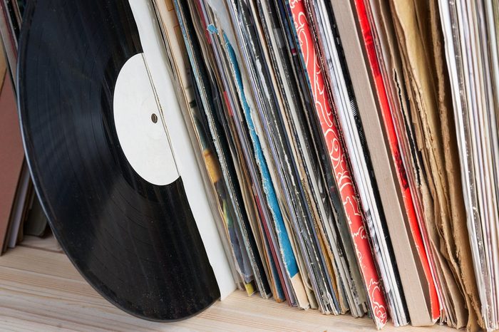 Retro styled image of a collection of old vinyl record lp's with sleeves on a wooden background. Browsing through vinyl records collection. Music background. Copy space.