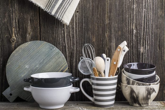 Cookware in gray and tools on a wooden kitchen shelf in the background rustic wooden wall. The horizontal design