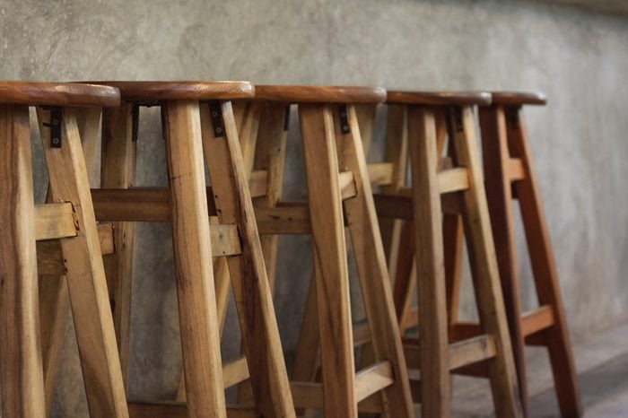 A high chair made of wood laid in front of a table made of mortar is like a bar.