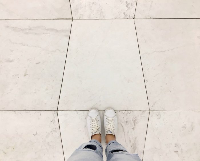 Top view selfie of sneakers shoes on white tiles floor background with copy space 