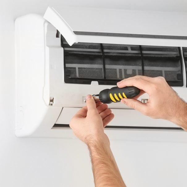 Male technician fixing air conditioner indoors