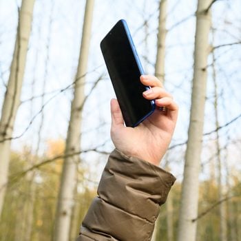 Close up of woman hand holding a the cell phone in the forest cell phone signal