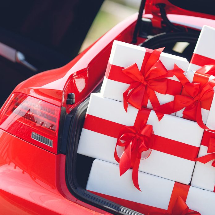 red luxury car with trunk full of gift boxes. presents for holiday. car, presents. holidays, happiness. street outdoor