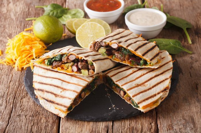 Mexican quesadilla with spinach, beans and cheddar cheese close-up on the table. horizontal