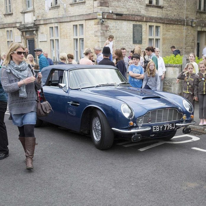 Prince Charles ' Aston Martin acts as a background for people to have their pictures taken standing next to it whilst the Prince was in the concert.