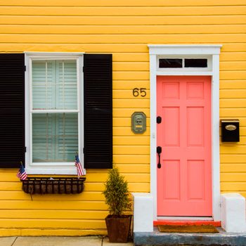coral painted front door on yellow house