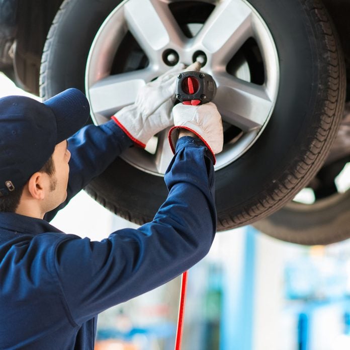 Mechanician-changing-car-wheel-in-auto-repair-shop