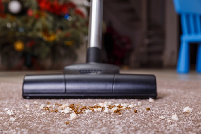 Vacuuming carpet with vacuum cleaner. Dirt on the rug. Housework service. Close up of the head of a sweeper cleaning device.