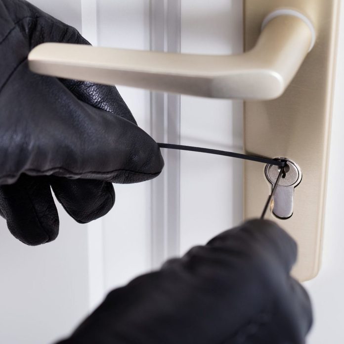 Close-up Of A Burglar With Gloves Picking Lock