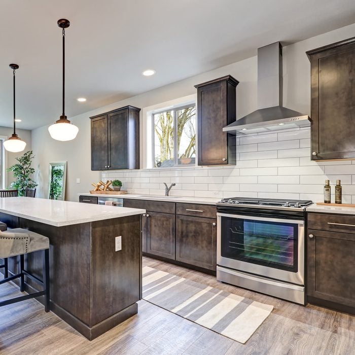 modern kitchen with dark cabinets and a white subway tile style backsplash