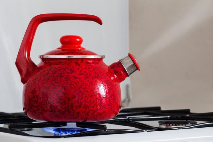 Tea kettle with boiling water on gas stove