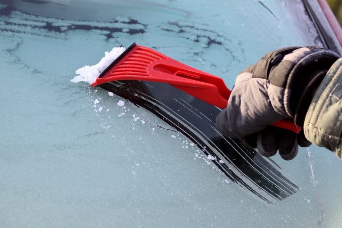 Scraping ice from the car window, with copy space