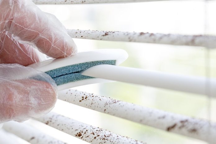 Spring cleaning, Dirty sections of white sun blinds and hand of worker who clean it up with special tool rubber protection glove window glass cleaning