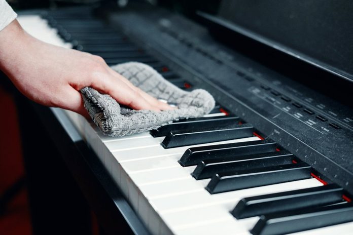dirty piano, wipe dust from a piano, a woman's hand with a rag for cleaning