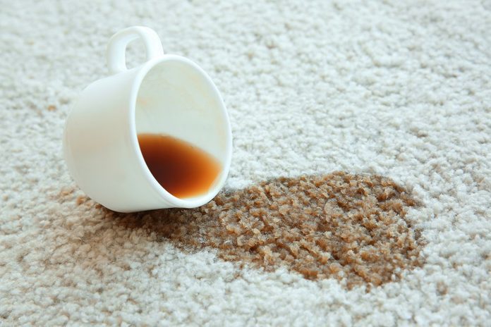 Cup of coffee spilled on white carpet, close up